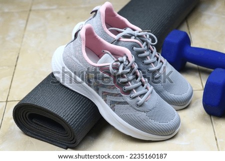 Grey Mattress, blue barbell and sport shoes on the floor. Indoor workout concept and healthy lifestyle. Sport equipment background.