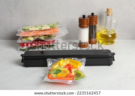 Sealer for vacuum packing with plastic bag of bell peppers on white table Royalty-Free Stock Photo #2235162457