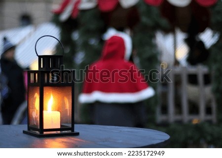 Small and bright lantern with the candle inside pictured at one of the tables at the Christmas Market in Riga, Latvia. 