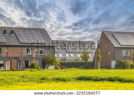 Row of modern family houses in contemporary street. New ecological neighborhood with solar panels. Small  gardens and private parking places. Street view in Heerhugowaard, Netherlands. Royalty-Free Stock Photo #2235186077