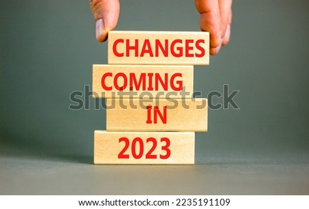 Changes coming in 2023 symbol. Concept word Changes coming in 2023 on wooden blocks. Businessman hand. Beautiful grey table grey background. Business and changes coming in 2023 concept. Copy space.