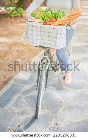 Selective focus. Unrecognizable young woman rides her dutch bike carrying fresh food in the basket. Healthy vegan lifestyle concept.