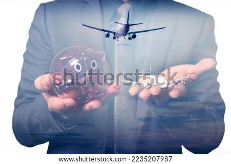 the double exposure image of the businessman holds the miniature airplane and piggy bank and overlay with airpland landing image. the concept of transportation, travel, business and technology