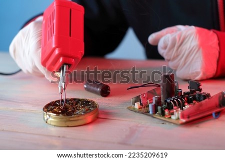 cleaning the soldering iron tip in rosin on the table by a person on a blue background Royalty-Free Stock Photo #2235209619