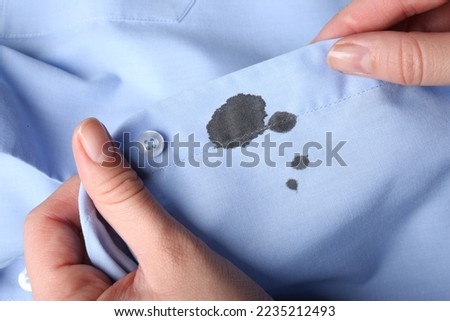 Woman holding shirt with black ink stain, closeup Royalty-Free Stock Photo #2235212493