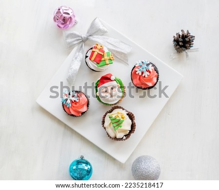Homemade christmas cute cupcakes or muffins with sapes of santa and trees on white christmas table
