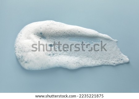 Smudge of white washing foam on color background, top view Royalty-Free Stock Photo #2235221875