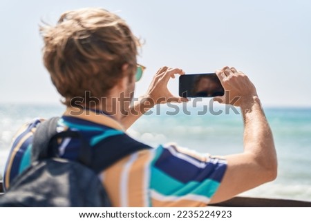 Young man tourist make photo by smartphone at seaside