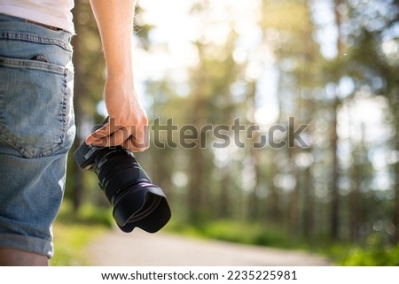 A photographer holding a camera in a park getting ready to take photos