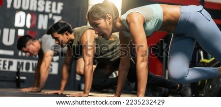 Group of young athlete male and female exercising together in fitness. Attractive handsome sportsman and sportswomen working out by push-ups to maintain strong muscle for health care in gymnasium. Royalty-Free Stock Photo #2235232429