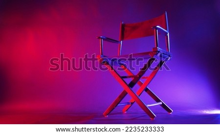Black Director chair use in video production or cinema industry in red and blue light color with black background.