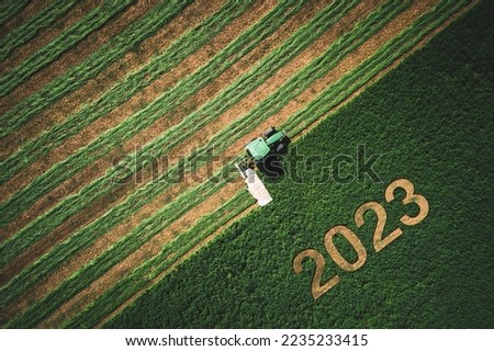 2023 Happy New year concept for agriculture, business, goals, success and new start banner. Industrial tractor on a green field. Royalty-Free Stock Photo #2235233415