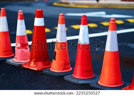 A number of red traffic cones, limiting the passage.