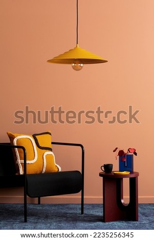 Warm and cozy living room interior with black armchair, round coffee table, patterned pillow, navy carpet, vase with dried flowers and personal accessories. Home decor. Template. 
