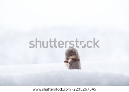 Hedgehog in the fog. Cute Little scared toy hedgehog with a knot in the snow