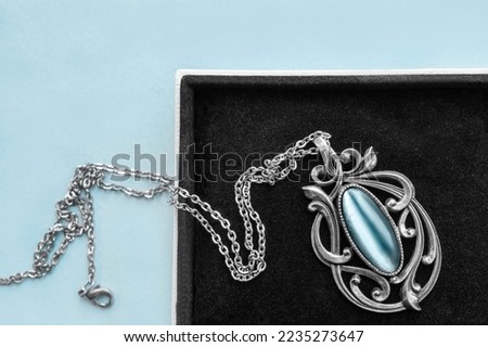 Vintage silver necklace with blue opal in jewel box on blue background