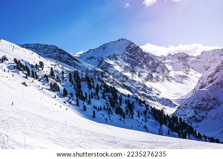 Ski tracks on snow covered mountain against sky. Idyllic view of forest on white landscape. Beautiful alps during winter.