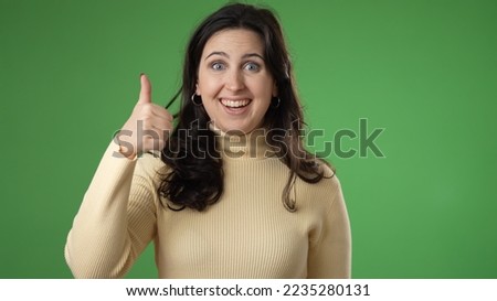 Portrait of excited, surprised smiling pretty young hipster woman 20s gives thumbs up smiling isolated on green screen background studio