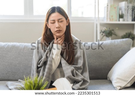 Sick, hurt or pain asian young woman, girl with sore throat, cough have a fever, flu and sneezing nose, runny sitting on sofa bed at home. Health care person on virus seasonal. Royalty-Free Stock Photo #2235301513