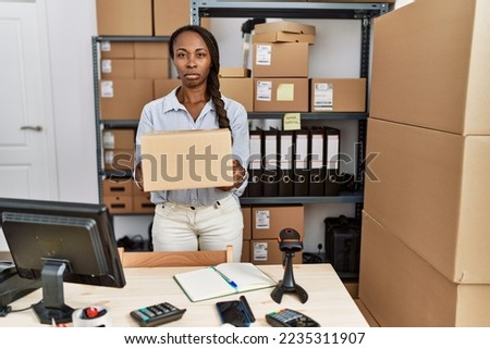 African woman working at small business ecommerce holding box skeptic and nervous, frowning upset because of problem. negative person. 