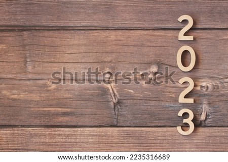 Wooden figures are located on a wooden background. New Year 2023. Copy space.