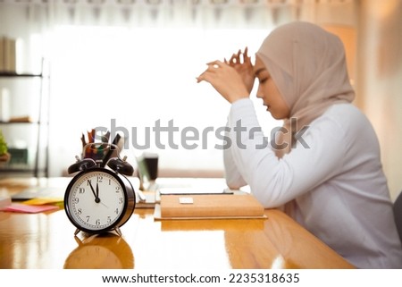 Background of Impatient muslim woman waiting to finish work, feeling tired and displeased. Serious upset person looking at watch to see deadline working delay. Hard working last night. Close up clock