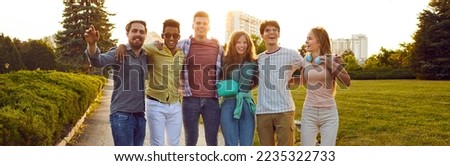 Happy young people enjoying summer, spending time outdoors and having fun together. Joyful excited diverse friends standing in the city park, hugging each other and smiling. Group portrait. Banner
