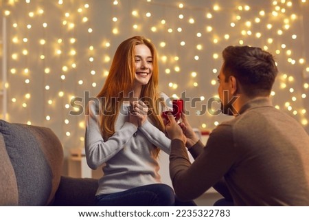 Will you marry me. Man in love kneels in front of a girl with a wedding ring in his hands and offers her marriage. Man holds a red box with a wedding ring in front of his beloved. Royalty-Free Stock Photo #2235322783
