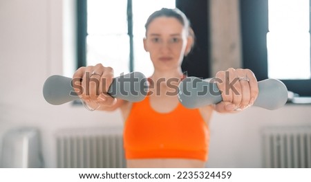 Strength and motivation.Young fit woman in sport cloth holding dumbbells in gum across from the window . health lifestyle. 