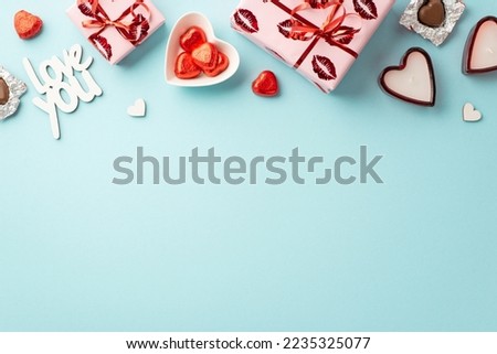 Valentine's Day concept. Top view photo of gift boxes heart shaped candles plate with chocolate candies and inscription love you on isolated pastel blue background with empty space