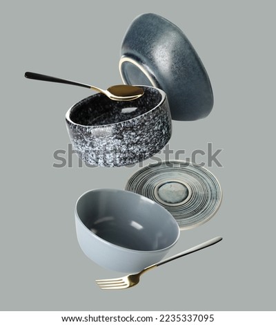 Flying clean dishes and cutlery on grey background Royalty-Free Stock Photo #2235337095