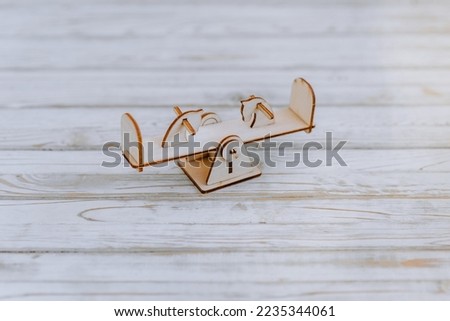 Small, miniature wooden homemade children's swing for balance, a toy from the playground constructor set, close-up in the studio. Photography, design, decor.