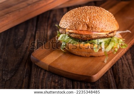 Grilled Chicken burger isolated on cutting board top view on dark background american fast food