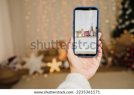 woman hand holding mobile phone indoor, taking picture of christmas decoration