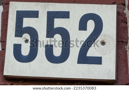 A sign on a wall with the number five hundred fifty-two-552