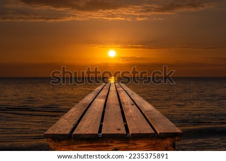 A wooden pier on the coast of the North Sea during a romantic sunset