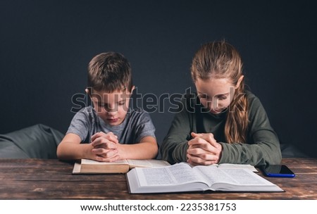 Children pray with folded hands. The Bible is open on the table. Prayer to pray. Teenagers Royalty-Free Stock Photo #2235381753