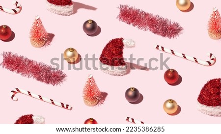 Trendy Christmas wallpaper with red New Year's decorations on pastel pink background. Xmas pattern made of shiny props.