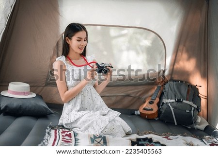 Asian traveller and photographer relax with her camera in camping trip inside her tent
