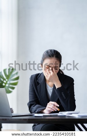 Asian businesswomen feel stressed at work when faced with hard work. Feeling headaches and eyestrain working on a laptop computer in the office. Royalty-Free Stock Photo #2235410181
