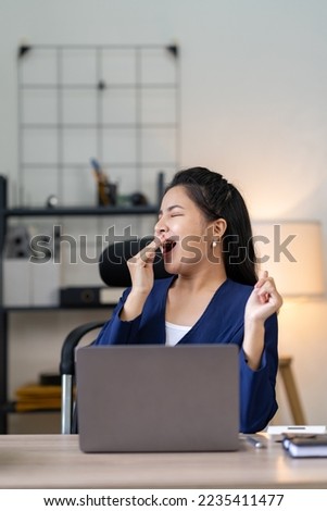 Asian businesswoman yawning while working on a laptop computer at the office woman in financial management concept Marketing in the online age.