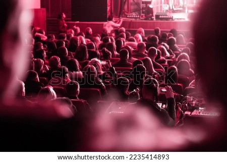 Defocused viva magenta. Color of the year 2023. Pantone. spectators sit in the hall and watch a concert. People in the auditorium watching the performance. Theater audience. Out of focus