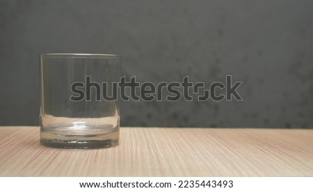 picture of a glass of water which is half-full standing on a brown wooden table