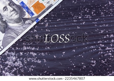 LOSS - word (text) on a dark wooden background, money, dollars and snow. Business concept (copy space).