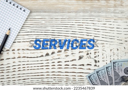 SERVICES - word (text) and dollars on a white wooden table, notebook, notepad. Business concept: buying, selling, commerce (copy space).