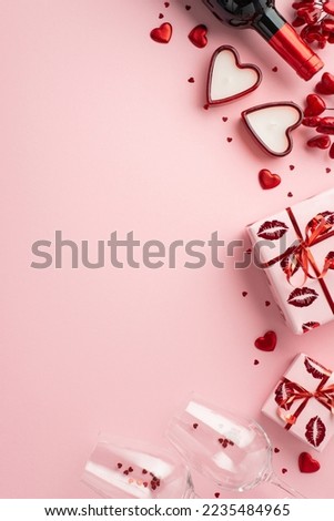 Valentine's Day concept. Top view vertical photo of wine bottle glasses with confetti present boxes and heart shaped candles on isolated pastel pink background with copyspace