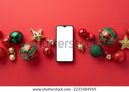 Christmas Day concept. Top view photo of smartphone star ornaments gold green and red baubles on isolated red background with blank space