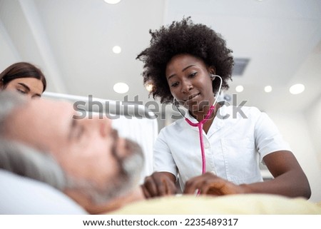 Senior patient on bed talking to African American female doctor in hospital room, Health care and insurance concept. Doctor comforting elderly patient in hospital bed or counsel diagnosis health. Royalty-Free Stock Photo #2235489317