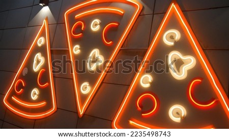Three big neon pizzas on the wall