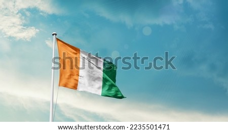 Ivory Coast national flag waving in beautiful sky. Royalty-Free Stock Photo #2235501471